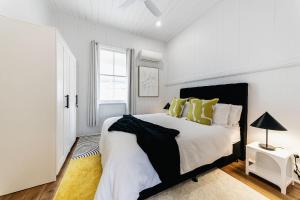 1 dormitorio blanco con 1 cama grande con almohadas amarillas en Urban Getaway Ipswich W Cottage, en Ipswich