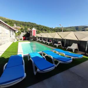 a group of blue lounge chairs next to a swimming pool at Casa do Loureiro - Apartamento in Paradela +16 photos