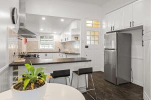 a white kitchen with a table and a refrigerator at 5 Bed 5 Bath Urban Getaway Ipswich Central in Ipswich
