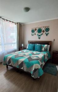 a bedroom with a bed with a green and gray comforter at Departamento Central 1D - Wifi - Parking in Antofagasta