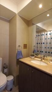 a bathroom with a sink and a toilet and a mirror at Departamento Central 1D - Wifi - Parking in Antofagasta