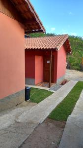 a red house with a trash can in front of it at Chalés Mimar Lumiar Suítes independentes in Lumiar