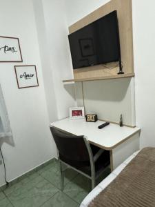 a bedroom with a desk with a television and a bed at Flats Linda Vista Mar in Macaé