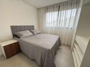 a bedroom with a bed and a large window at Apto em Home Clube na Praia de Palmas in Governador Celso Ramos +24 photos