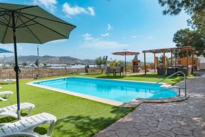 a swimming pool with chairs and an umbrella at Cortijo Pinar 2 in Níjar