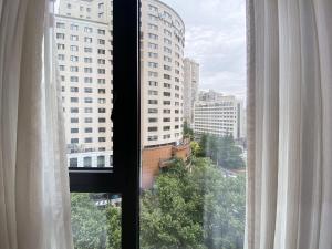 a window with a view of a city with tall buildings at Tyms APT Hengshan RD Near IAPM K11 Line9 in Shanghai