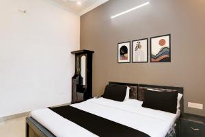 een slaapkamer met een bed met drie foto's aan de muur bij Hotel O IIDM ECO CENTRE in Lucknow