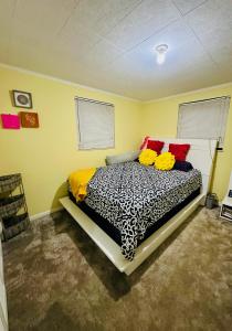 a bedroom with a black and white bed with red pillows at Riviera Haven, 10 Minutes from the Beach, Coastal Town, Quaint & Comfy in Riviera Beach