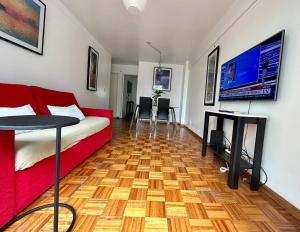 a living room with a red couch and a wooden floor at Sarmiento Home in Buenos Aires