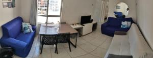 a living room with a table and two blue chairs at Recanto dos Milionários in Ilhéus