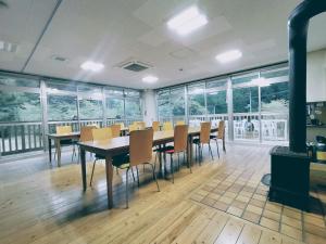 uma sala de jantar com mesas, cadeiras e janelas em 山村自然楽校しもなの郷 em Nanokawado