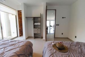 a person with a hat on a bed in a room at Angelina 28 Beachfront and Family Apartments - Modern and Relaxing Long Stays - 20 min from Cancun Airport in Puerto Morelos