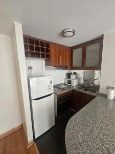 a kitchen with a white refrigerator and wooden cabinets at San Ignacio Suite Apoquindo MQ3 in Santiago +12 photos