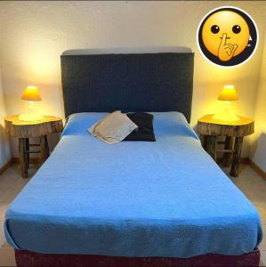 a bed with a blue comforter and two side tables at das gelbe haus in Los Reartes