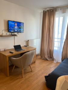 a room with a desk with a laptop and a television at La chatillonnaise in Châtillon
