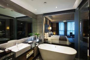 un bagno con una grande vasca e una camera da letto di Millennium Hotel Fuqing a Fuqing