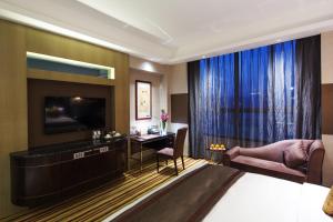 una camera d'albergo con un letto, una scrivania e una televisione di Millennium Hotel Fuqing a Fuqing
