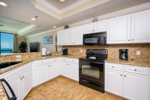 une cuisine avec des armoires blanches et des appareils noirs dans l'établissement Phoenix IX 506 condo, à Orange Beach