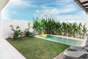a backyard with a swimming pool and a yard with plants at Villa Imperial Bliss in Uluwatu