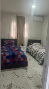 Un dormitorio con dos camas y suelo de baldosas. en Los laureles, en Puerto Plata