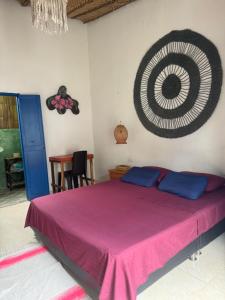a bedroom with a bed with purple sheets and a painting on the wall at HOTEL RENASCI PALOMINO in Palomino