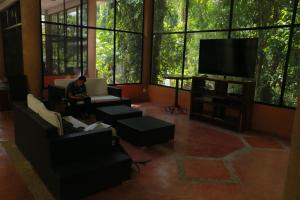 a man sitting in a living room with a tv at Canto de la Selva Jungle Lodge Selva Lacandona Chiapas in Galaxia