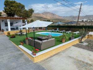 a backyard with a pool with a couch and an umbrella at Cortijo El Pinar 1 in Níjar