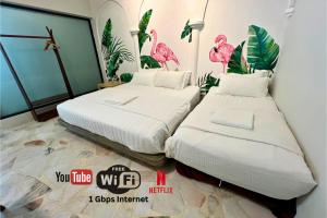 two beds in a room with pink flamingos on the wall at 5 mins walking to East Coast Mall JW Guest House in Kuantan