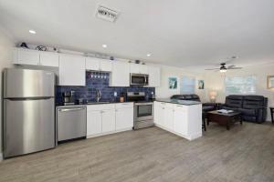 Una cocina con gabinetes blancos y un refrigerador de acero inoxidable. en Sun Set By The Sea 3052, en Fort Myers Beach