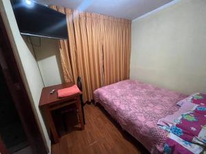a small bedroom with a purple bed and a table at Habitación con baño privado in Ayacucho