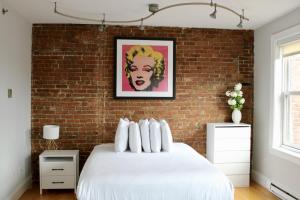 ボストンにあるStylish Downtown Studio in the South End, #8の白いベッドとレンガの壁が備わるベッドルーム1室が備わります。