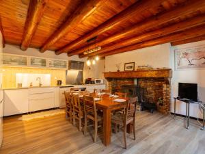 a kitchen and dining room with a table and a fireplace at Maison à Génos pour 8, proche lac, jardin et poêle à bois - FR-1-695-73 in Génos
