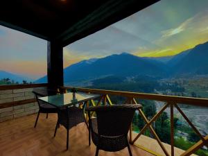 un tavolo e sedie su un balcone con vista sulle montagne di The Kartik Villa, Manali - A Beautiful Cottage in the Clouds towards Snow Capped Mountains a Manāli