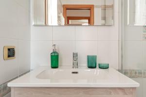 a bathroom sink with two green glasses on it at Cozy Retreat in Coastal Livorno in Livorno +17 photos