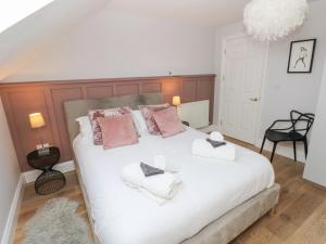 une chambre avec un grand lit blanc avec des oreillers roses dans l'établissement Cambrie, à Tenby 24 autres photos