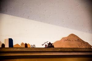 a shelf with drawings of buildings and a mountain at Dot Hostel Nagano in Nagano