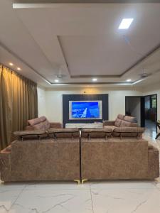 a living room with couches and a flat screen tv at Aarvis House in Mahabaleshwar