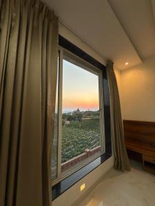 a room with a window with a view of a field at Aarvis House in Mahabaleshwar