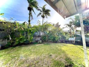 La Villa Des Lys avec jacuzzi في سان دوني: حديقه خلفيه فيها سياج والنخيل وساحه