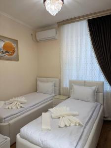 two beds in a room with white furniture and a chandelier at Podshoh guest house in Samarkand +92 photos