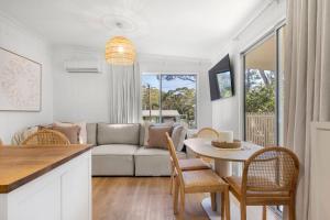 un salon avec un canapé, une table et des chaises dans l'établissement Piccolo Cottage - Firepit - 4 Mins Walk to Beach, à Callala Beach