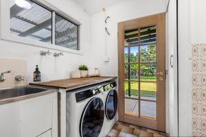 une cuisine avec une machine à laver et un évier dans l'établissement Piccolo Cottage - Firepit - 4 Mins Walk to Beach, à Callala Beach