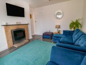 ein Wohnzimmer mit einer blauen Couch und einem Kamin in der Unterkunft Field Cottage in York