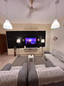 a living room with a couch and a flat screen tv at Electrifying 2 BHK Getaway in Bengaluru