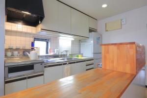 a kitchen with white cabinets and a wooden counter top at Hostel FIVE ホステルファイブ in Kochi