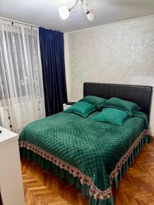 ein Bett mit grüner Bettdecke und Kissen im Schlafzimmer in der Unterkunft Zen Apartment in Galaţi