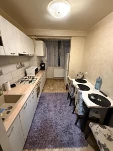 eine Küche mit weißen Schränken und einem lila Teppich in der Unterkunft Zen Apartment in Galaţi