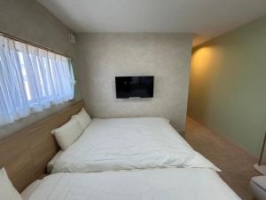 ein kleines Schlafzimmer mit einem Bett und einem Flachbild-TV in der Unterkunft SANDBoX in Oshima