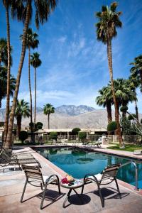 una piscina con 2 sillas y palmeras en Desert Isle Resort, a VRI resort, en Palm Springs