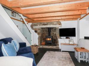 a living room with a stone fireplace and a tv at 2 Rose Cottage in St. Agnes 